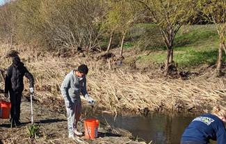 A group of students with buckets help clean a creek in Pleasanton during a Living Arroyos event.